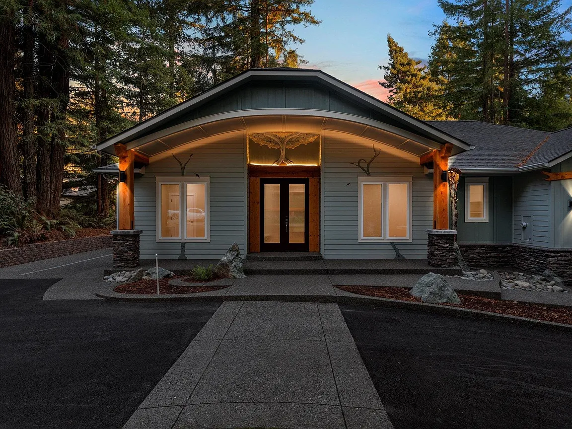 A Marshall Jones custom home glowing at dusk, framed by towering redwoods